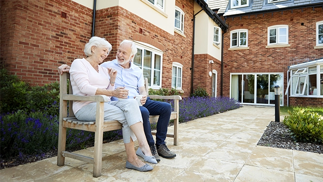 A happy senior couple sitting on a bench outside.