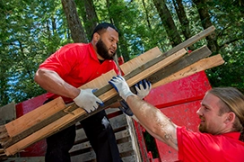 Two Junk King professionals loading boards onto a truck.