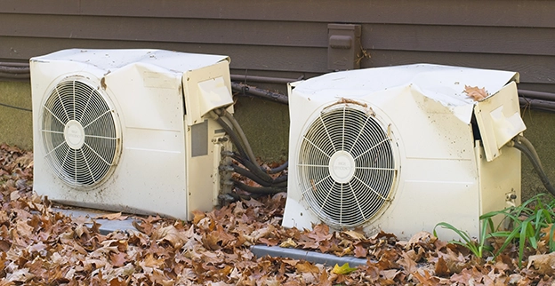 Two old air conditioners sitting outside of a home.