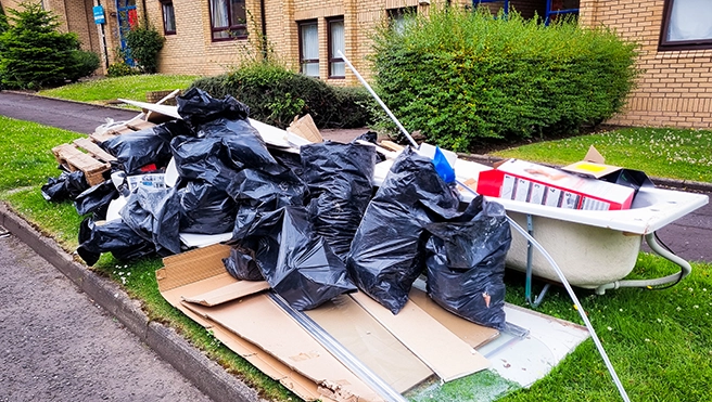 Pile of junk sitting outside of an apartment building.