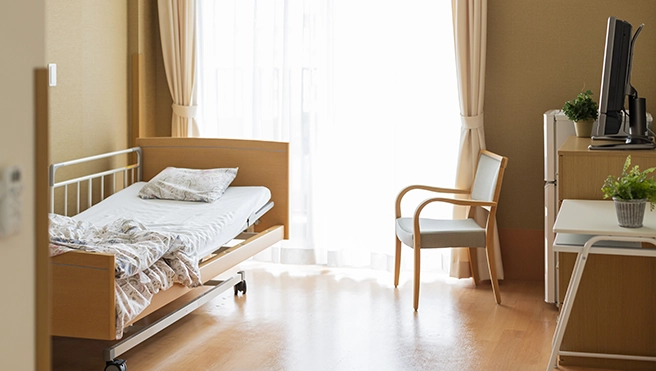 Room in a senior living facility with a bed and chair.