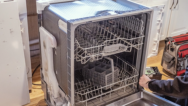 An open dishwasher removed from a cabinet.