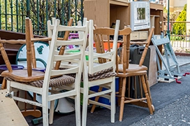 A pile of wooden chairs outside of a home.
