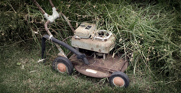 An old rusted lawnmower that is no longer running.