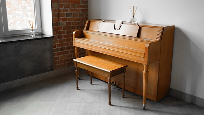 Brown piano sitting against a wall.