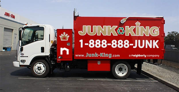 Red Junk King dump truck parked at a recycling facility.