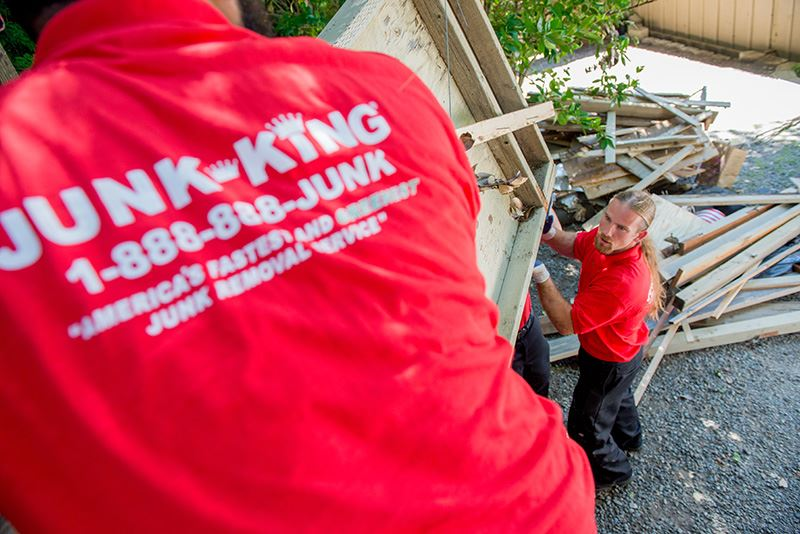 junk king workmen in red company shirts removing old home debris