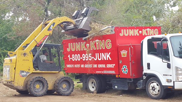 bobcat loading tree and yard trimmings onto a junk king truck