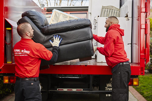 Junk King Servicemen loading sofa onto a junk king truck