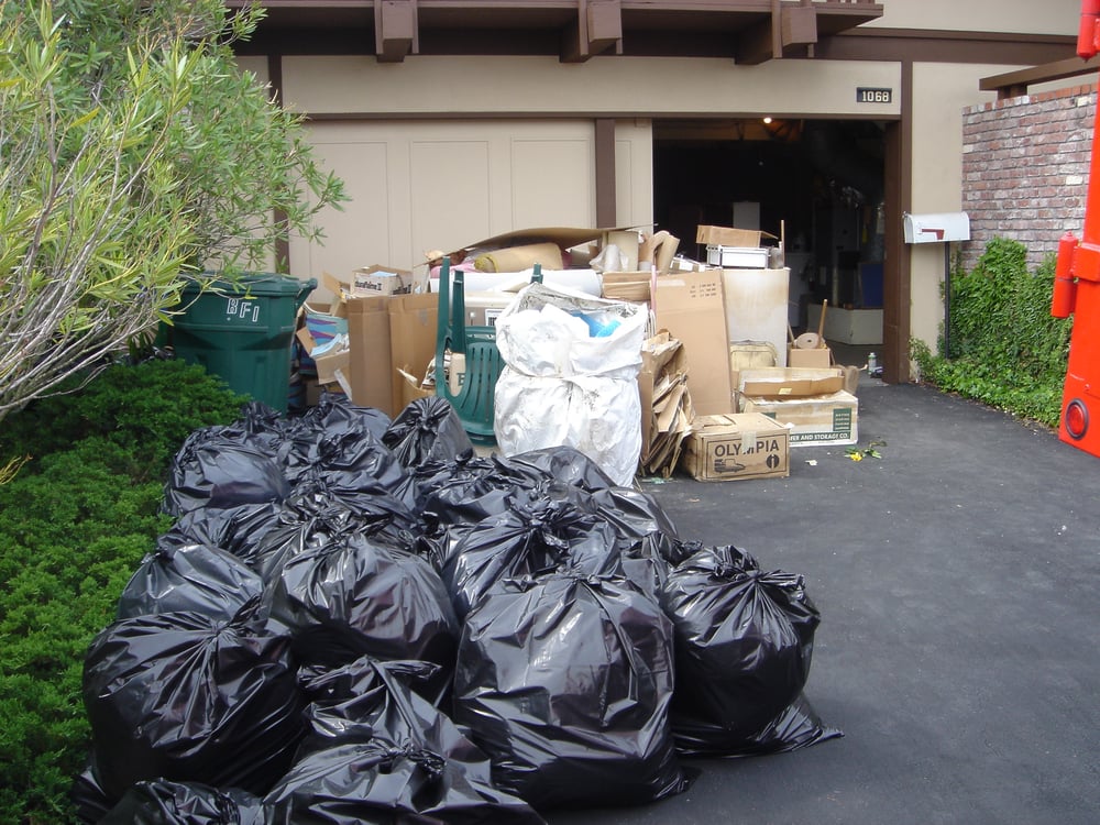 piles of garbage in black bags and old wooden debris in background