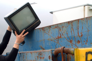female hand placing small tv monitor in dumpster