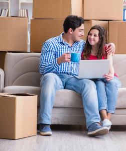 couple sitting on sofa with boxes stacked behind