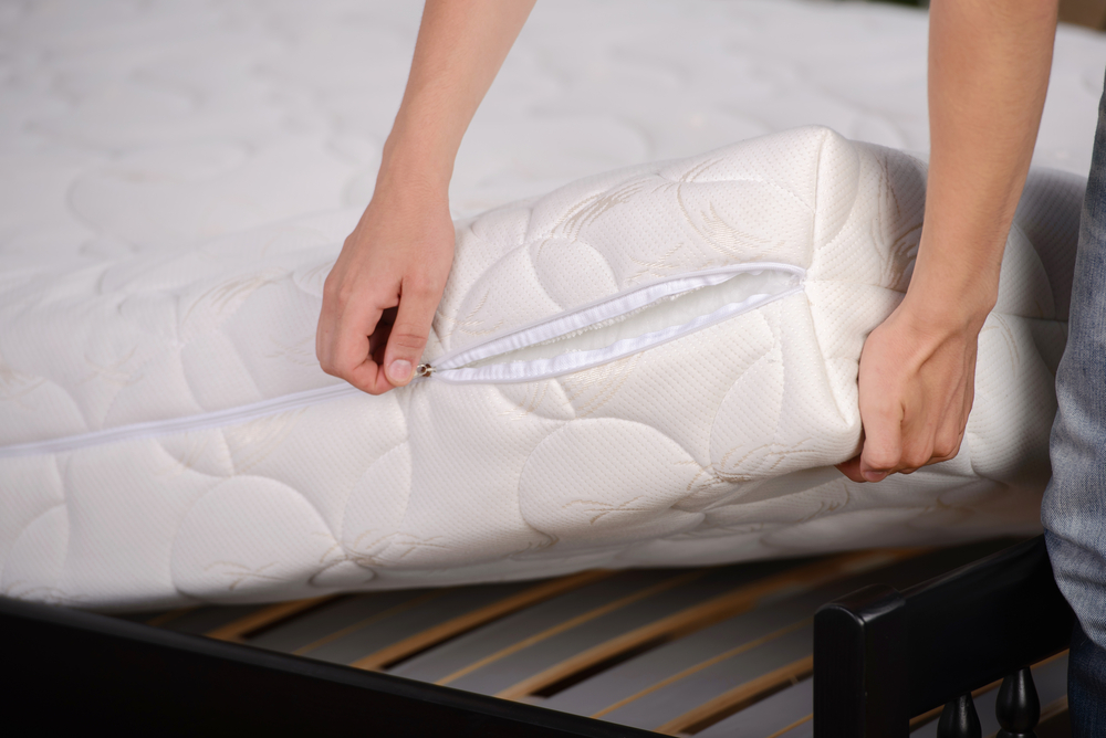 two hands lifting white mattress off bed