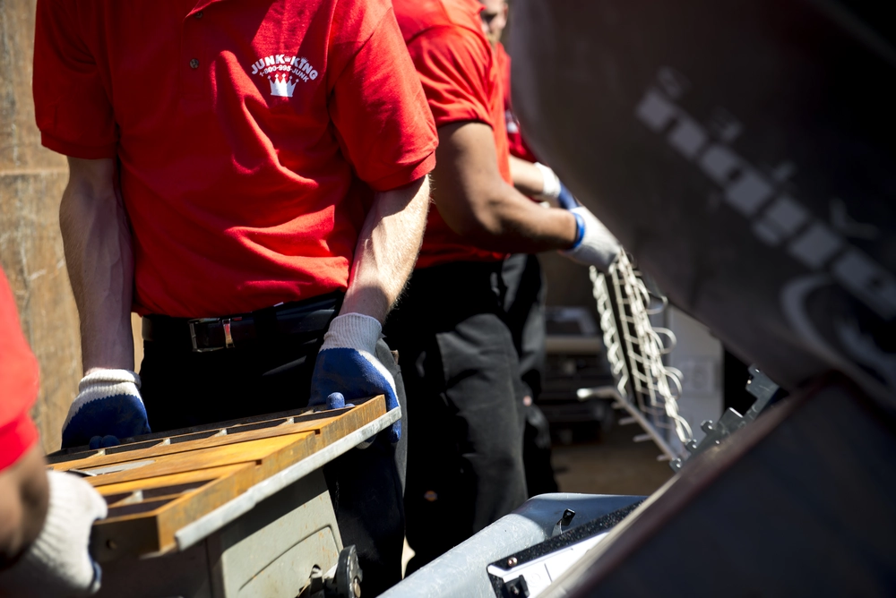 Junk King crew disassembling and hauling junk furniture during a full-service pickup