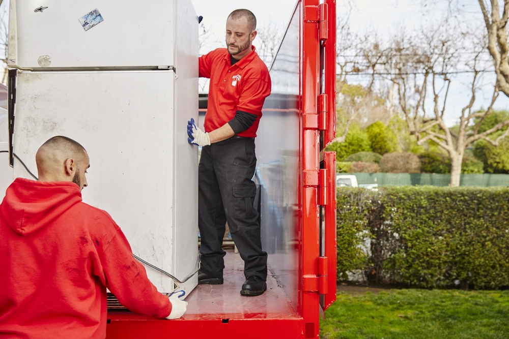 Junk King crew removing an old refrigerator during a full-service appliance pickup