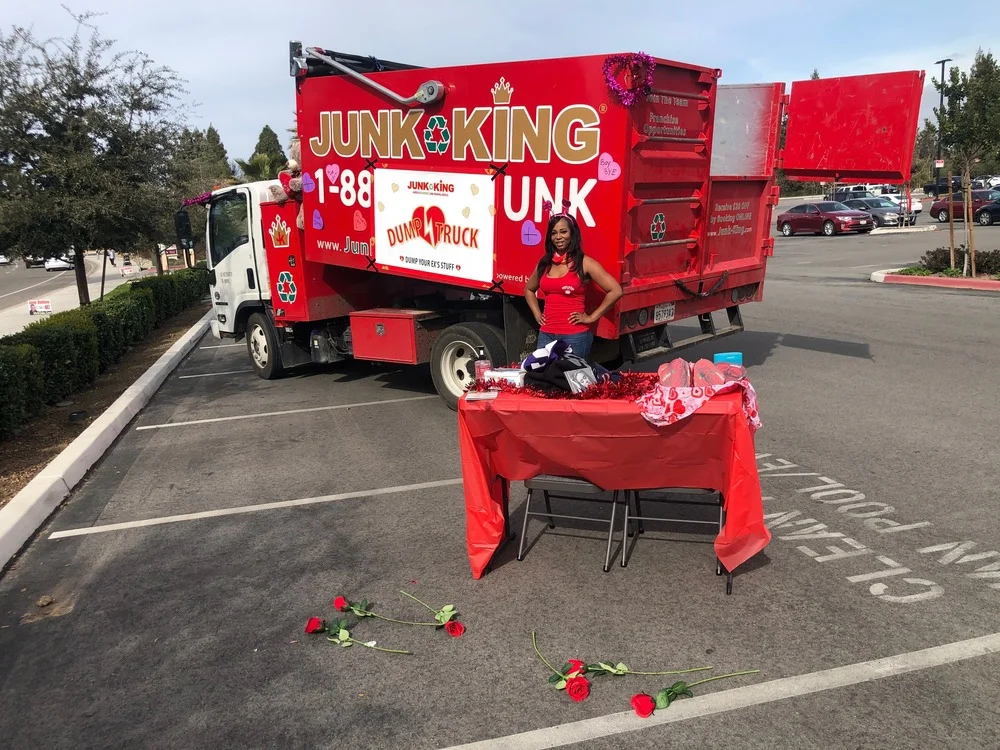 Woman posing in front of Junk King Dump Truck with a Valentine's theme.