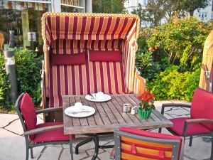 Outdoor seating area with a wooden table, red chairs, and a striped canopy chair.