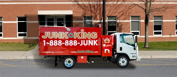Junk king truck parked in front of a brick building.