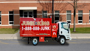 Junk king truck parked in front of a brick building.